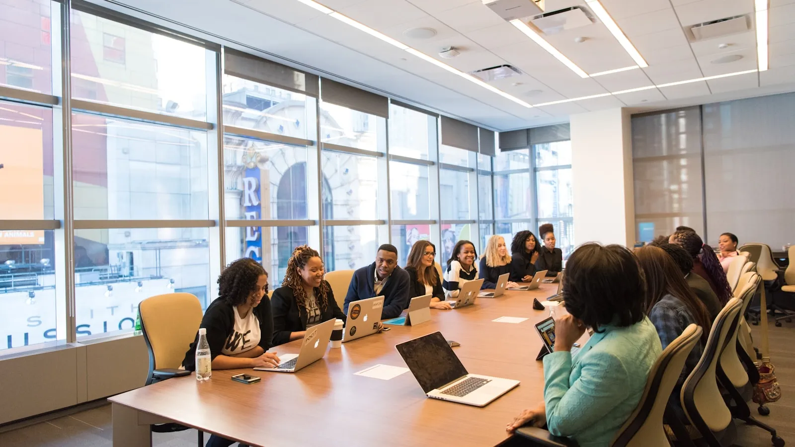 A group of colleagues sitting around a wooden table with laptops during a planning meeting