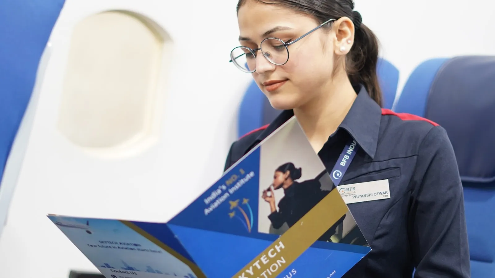 A woman seated on an airplane reading aviation training materials