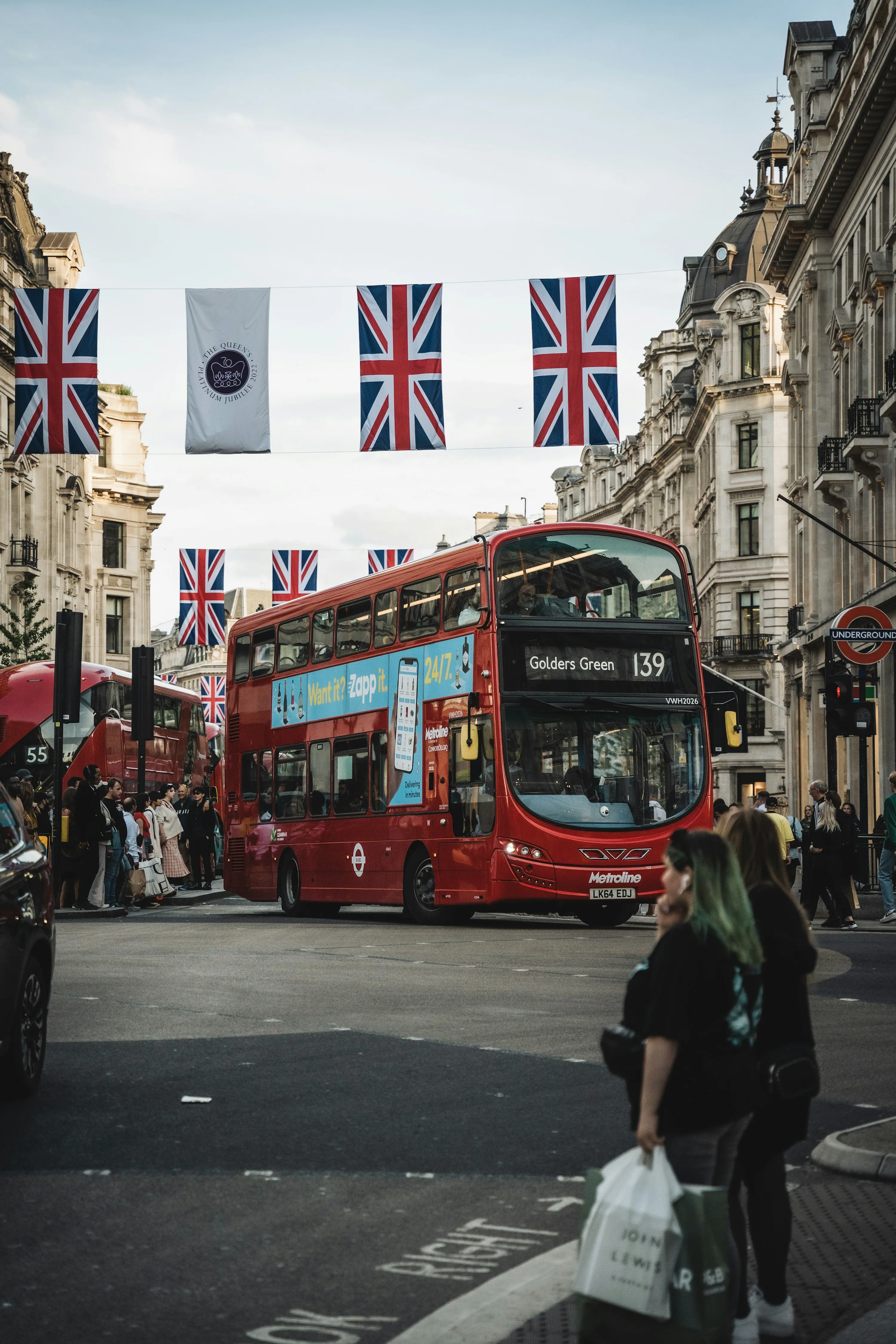 A red London double-decker bus driving along a city street