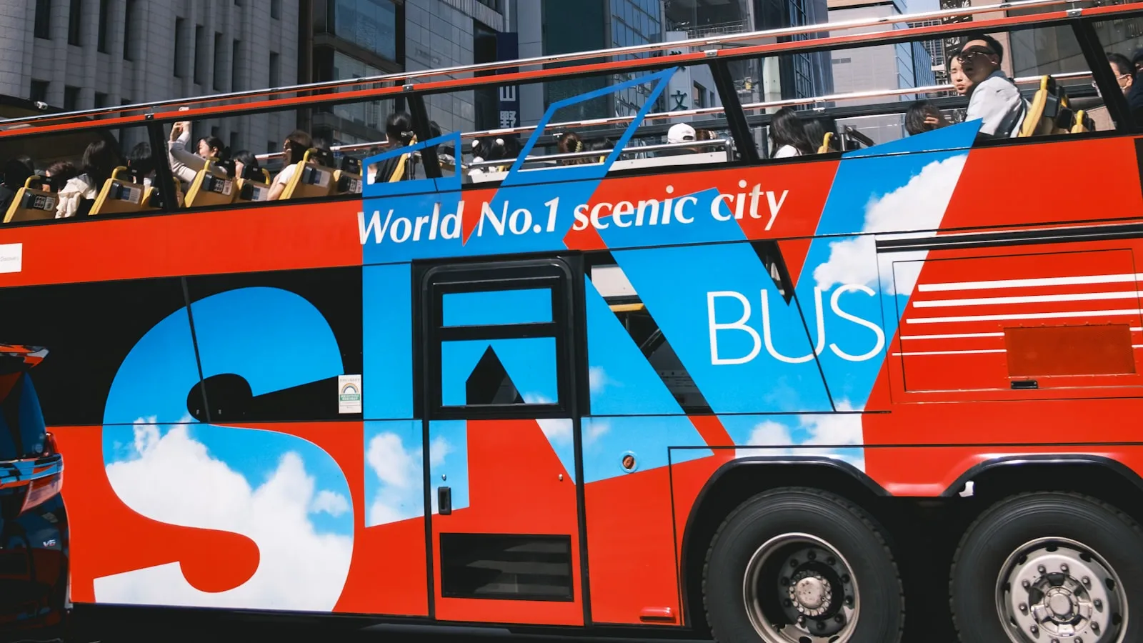 A red double-decker bus driving down a city street