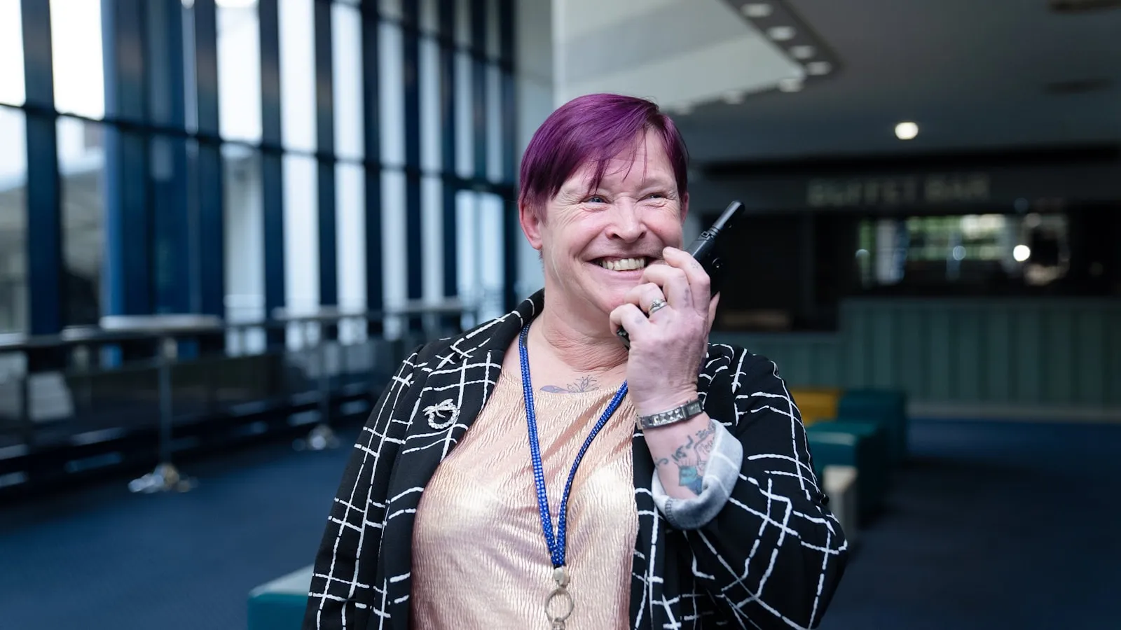 A smiling employee holding a handheld device while talking with colleagues